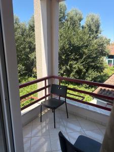 a chair on a balcony with a view of trees at Kodra Apartament in Golem