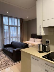 a kitchen and a living room with a bed and a couch at Urban Awe Apartment- iTowers 18th Floor in Gaborone