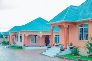 a house with a green roof and pink at MIAMi VILLA HOTEL in Mpanda
