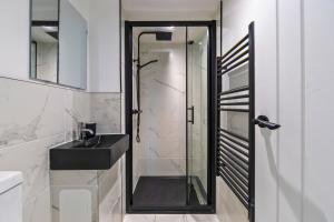 a bathroom with a glass shower and a black sink at New 3 Bedroom Flat Close to Station in Chepstow