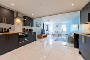 a kitchen with black cabinets and a living room at New 3 Bedroom Flat Close to Station in Chepstow +15 photos