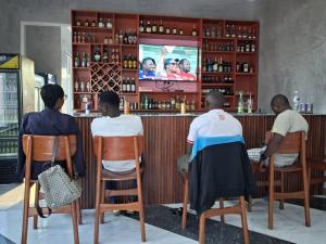 a group of people sitting in chairs at a bar at MIAMi VILLA HOTEL in Mpanda +9 photos