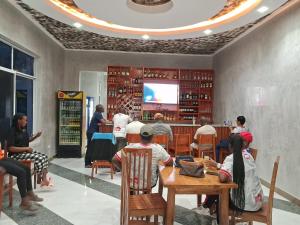 a group of people sitting at tables in a restaurant at MIAMi VILLA HOTEL in Mpanda