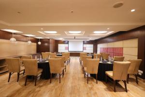 a conference room with tables and chairs and a screen at The Arcadia Coimbatore Airport in Coimbatore