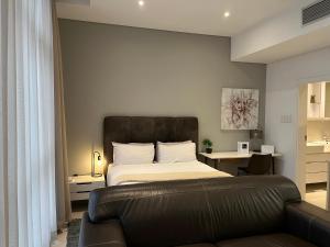 a bedroom with a bed and a leather couch at Urban Awe Apartment- iTowers 18th Floor in Gaborone