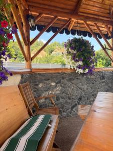 a patio with two chairs and a stone wall with flowers at Casa Petrişor in Corbi