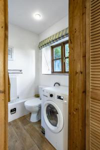 a bathroom with a washing machine and a toilet at Finest Retreats - The Little Barn in Great Somerford
