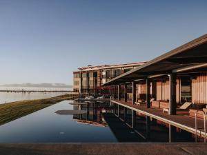 a building with tables and chairs next to a body of water at The Sebel Yarrawonga Silverwoods in Yarrawonga