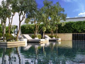 a pool of water with lounge chairs and trees at Pullman Bandung Grand Central in Bandung