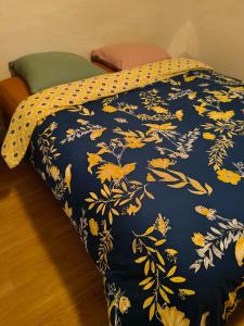 a bed with a blue blanket with yellow leaves at Chambre d'hôte Mont mouton in Laferté-sur-Amance