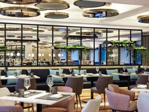 a restaurant with tables and chairs in a room at Athens Capital Center Hotel - MGallery Collection in Athens