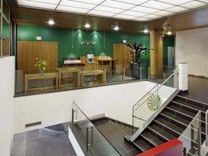 a lobby with stairs and a green wall at Mövenpick Hotel Zurich Airport in Glattbrugg