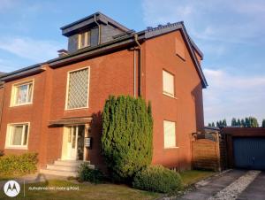 a red brick house with a bush in front of it at Ferienwohnung Fuchsbau in Werne an der Lippe