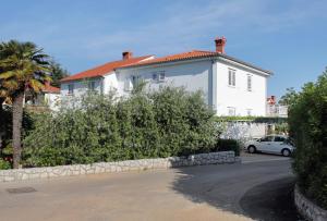 a white house with a car parked in front of it at Rooms with a parking space Krk - 5371 in Krk