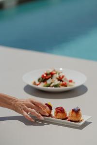 a person holding a plate with a plate of food at Kasimatis by La Perla - Adults Only in Imerovigli