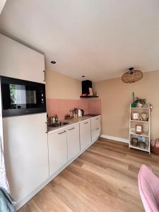 a kitchen with white cabinets and a sink at De Strandloper in Petten