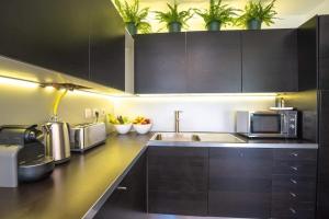 a kitchen with black cabinets and stainless steel appliances at PortugalActive Beach Flat in Viana do Castelo