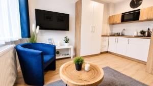 a living room with a blue chair and a table at Studio Cicha in Krynica Zdrój