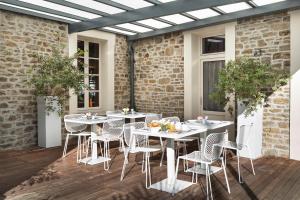 un patio al aire libre con mesas y sillas blancas en Hotel Eden, en Saint-Malo