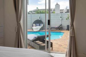 a bedroom with a view of a swimming pool through a window at Vida Tranquila Guest House in Welgelegen