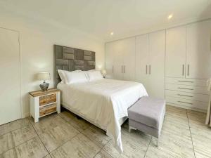 a white bedroom with a large bed and a chair at Vida Tranquila Guest House in Welgelegen