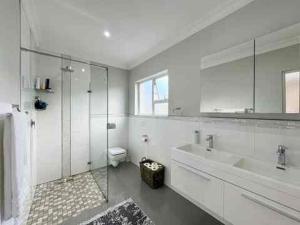 a white bathroom with a sink and a shower at Vida Tranquila Guest House in Welgelegen
