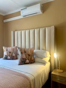 a bedroom with a bed with a white headboard and pillows at Piink Lopez in Manzini +36 photos