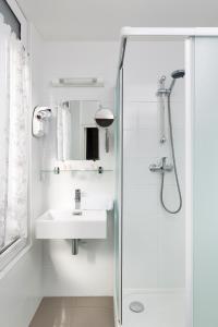 La salle de bains blanche est pourvue d'un lavabo et d'une douche. dans l'établissement Hotel Eden, à Saint-Malo