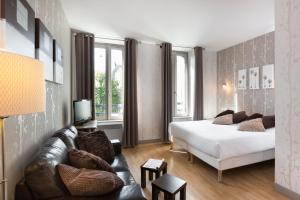 een slaapkamer met een bed en een bank bij Hotel Eden in Saint-Malo