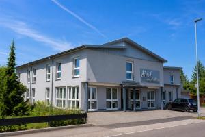 a white building with a car parked in front of it at Hotel am Hardtsee in Ubstadt-Weiher
