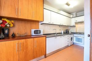 a kitchen with white cabinets and a microwave at Ocean view Cabedelo Beach Duplex in Viana do Castelo +17 photos