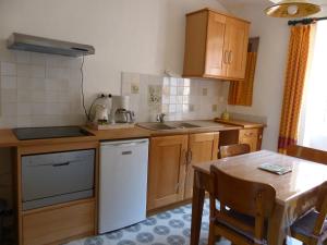 a kitchen with wooden cabinets and a table with a sink at Brimborion in Alba-la-Romaine