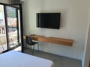 a bedroom with a desk with a television on a wall at Lucciola Boutique Rooms in Budva