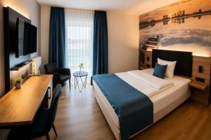 a hotel room with a large bed and a desk at Hotel am Hardtsee in Ubstadt-Weiher