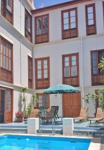 a hotel with a pool and chairs and an umbrella at Hotel Alhambra in La Orotava