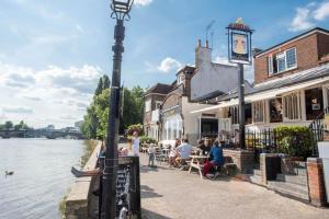 a group of people sitting at tables next to a river at Courtyard Oasis in London