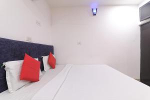 a white bed with red and white pillows on it at Simar Residency in Lucknow