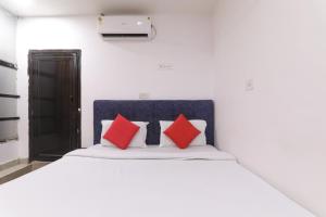 a bedroom with a white bed with red pillows at Simar Residency in Lucknow