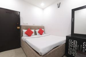 a bedroom with a bed with red pillows and a tv at Simar Residency in Lucknow