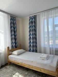 a bedroom with a bed with blue and white curtains at Kochkor valley in Kochkorka