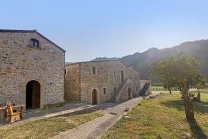 a group of stone buildings in a field with a tree at Fattoria San Pio in Naso