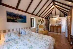 a bedroom with a large bed and a kitchen at Rincón de los Abanes - Finca Casa Jardín-VV in Las Lagunas