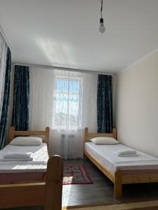 two beds in a bedroom with a window at Kochkor valley in Kochkorka