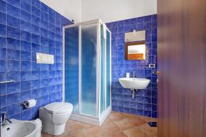 a blue tiled bathroom with a toilet and a sink at Fattoria San Pio in Naso