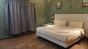 a bedroom with a large bed with white sheets at FabHotel Elite Residency in Vasai