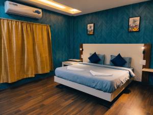 a bedroom with a bed with blue walls at FabHotel Elite Residency in Vasai