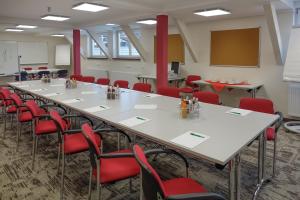 a conference room with a long table and red chairs at Hotel Thüringenschanze in Oberhof