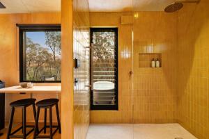 a bathroom with a shower with a sink and stools at HeartStone Hill - Tiny House in Castlemaine +29 photos