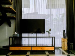 a flat screen tv on a stand in front of a window at Edy's Farm Cottage in Jabon