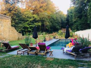 a backyard with a swimming pool with chairs and a man sitting on a couch at Effet Lodge in Saint-Cyr-au-Mont-dʼOr
